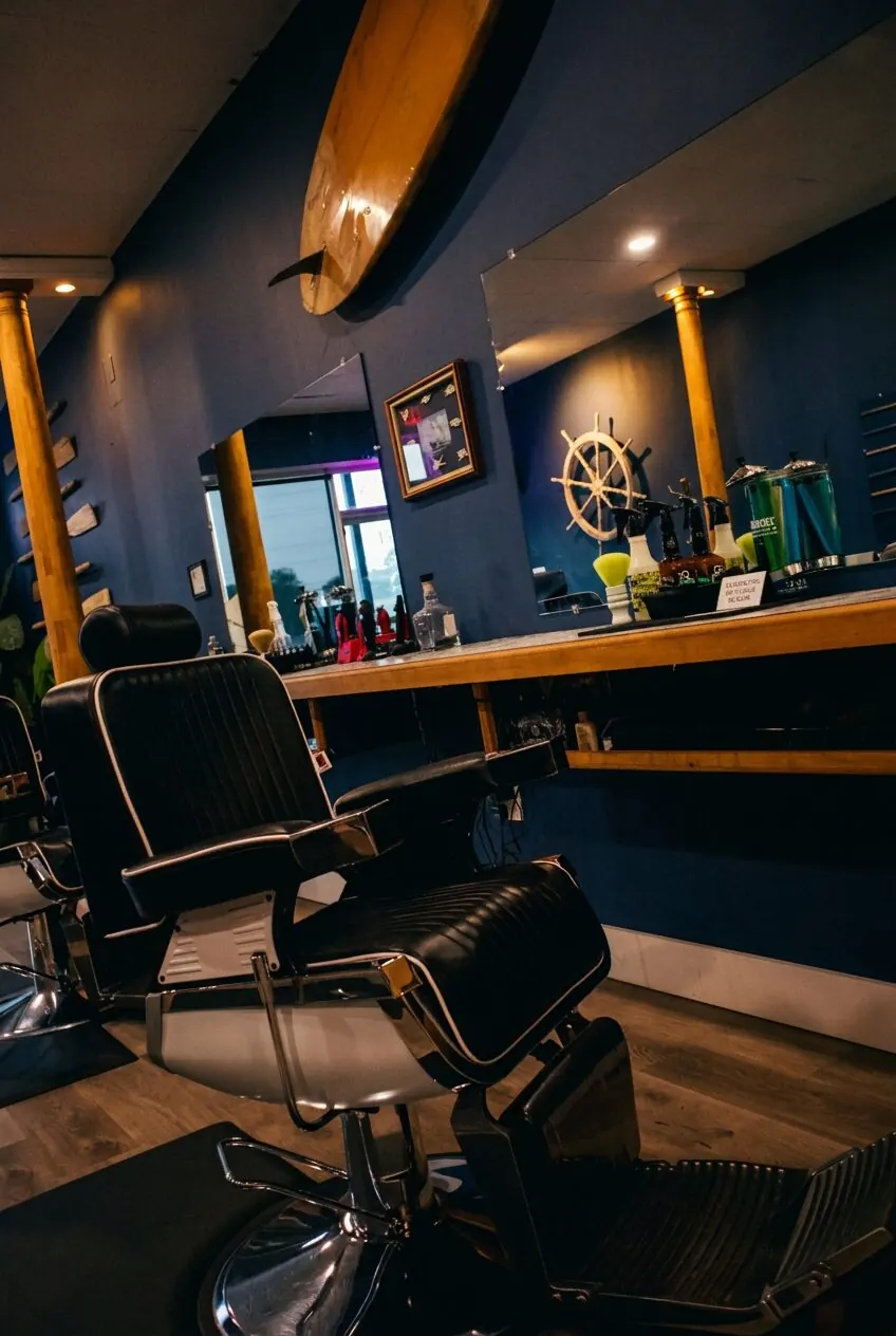 Coastal station — black leather barber chair, surfboard and ship wheel decor