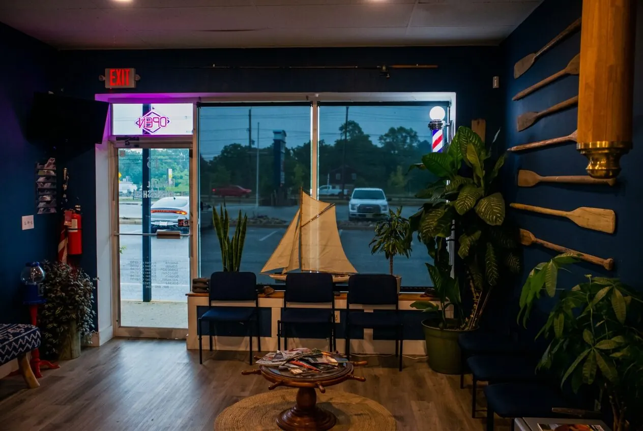 Coastal waiting area — navy walls, sailboat model, oars, and ship-wheel table